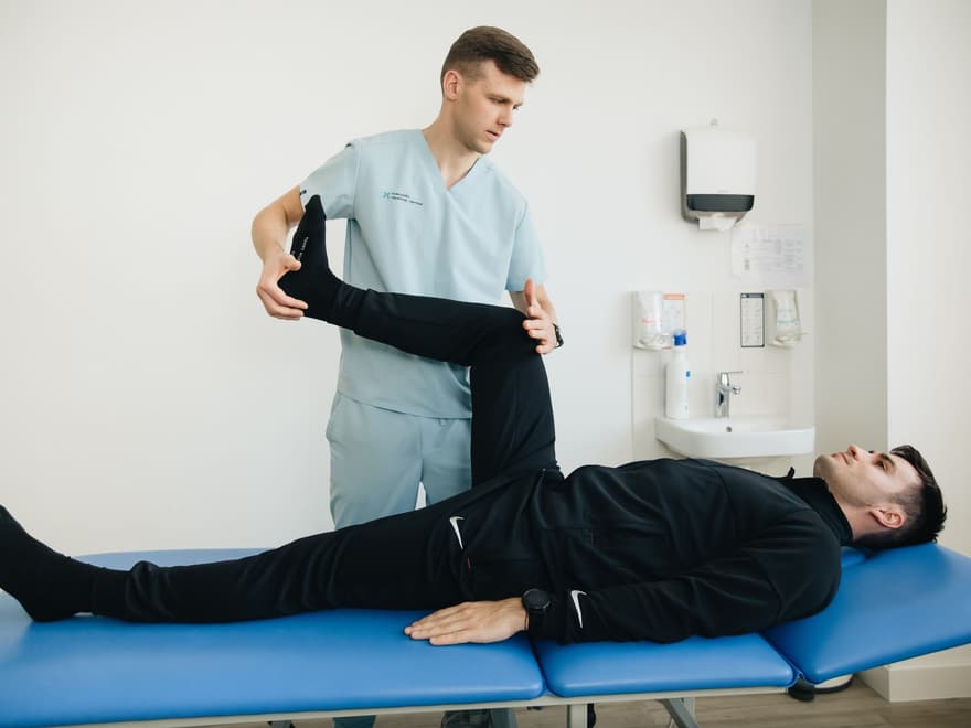 Physiotherapist stretching a patient's leg on a treatment table