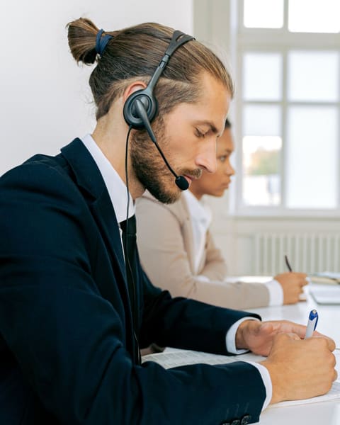 Receptionist in a suit taking notes on a call